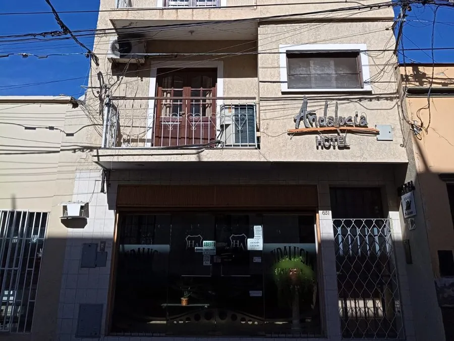 Entrada del Hotel Andalucía en Alberdi 651, con el cartel del hotel sobre la puerta vidriada