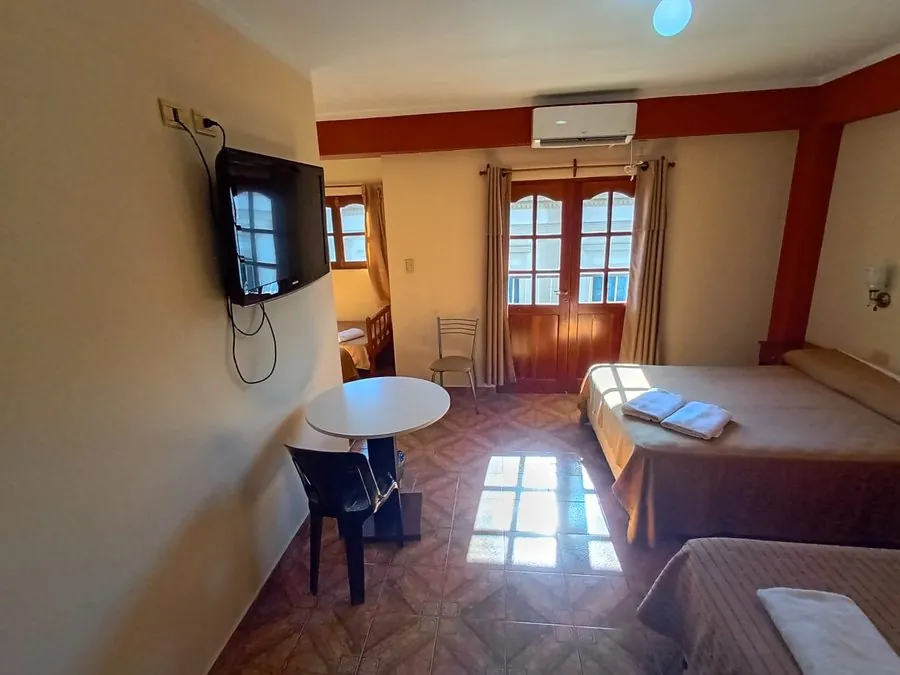 Habitación con luz natural, puerta-ventana al balcón, aire acondicionado, TV y mesa